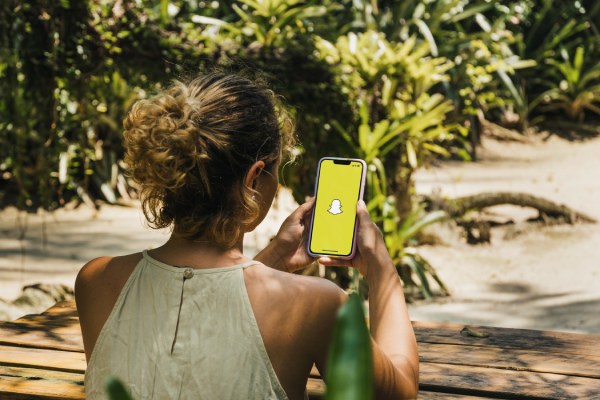 Girl in the park holding a smartphone with Snapchat app on the screen