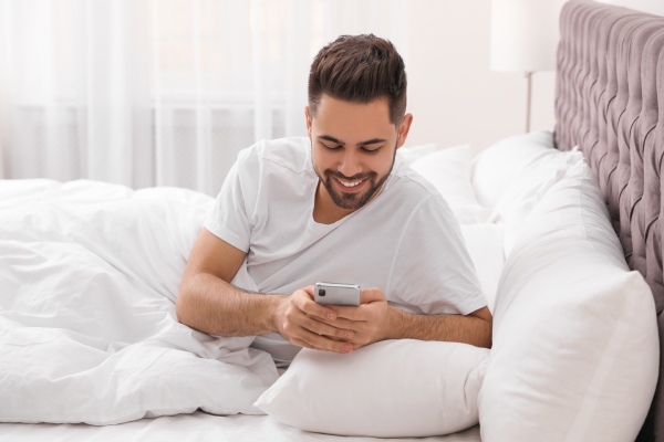 man with iPhone in bed